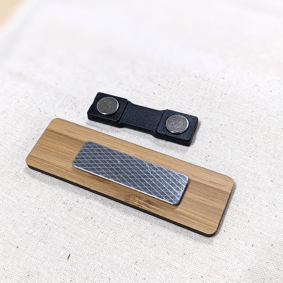 Wooden name badge and black magnet on a textured surface