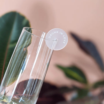 A frosted acrylic drink tag engraved with the text DRUNK IN LOVE on a wine glass