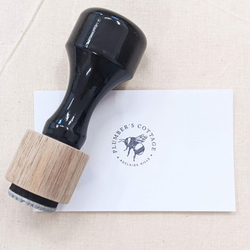 Round rubber stamp with logo stamped in black on a white card